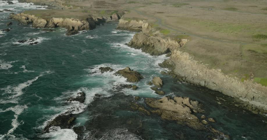 Aerial view of a bay with waters crashing against the rocky coast