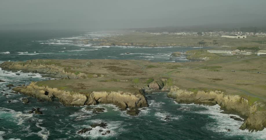 A rugged coastal landscape with rocky cliffs and waves crashing against them