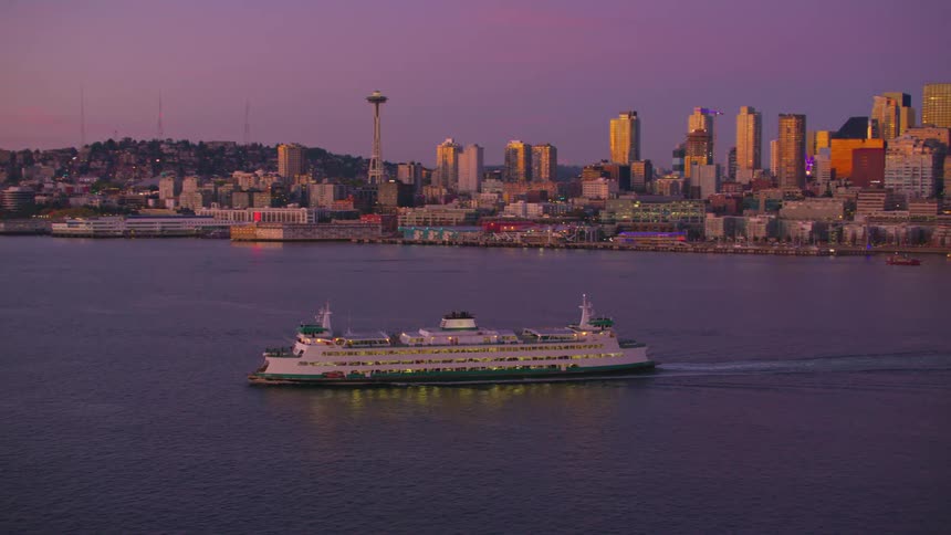 Aerial view of a boat traveling across the ocean with a city in the background