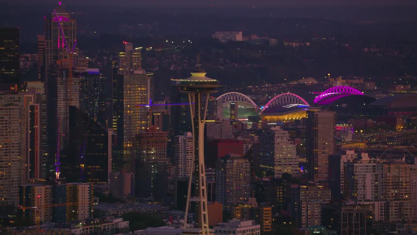 Iconic space needle stands out against seattles vibrant night scene while the purple lights of the stadiums illuminate the city in an urban spectacle