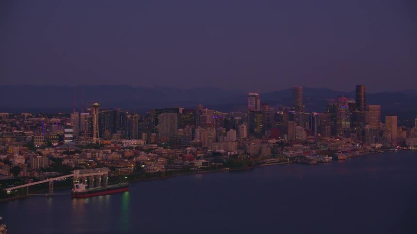 Seattle shines under the night sky with the space needle and skyscrapers reflecting vibrant lights over the serene waters of the bay
