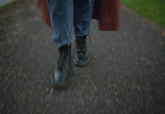 Person in black leather boots walking on asphalt