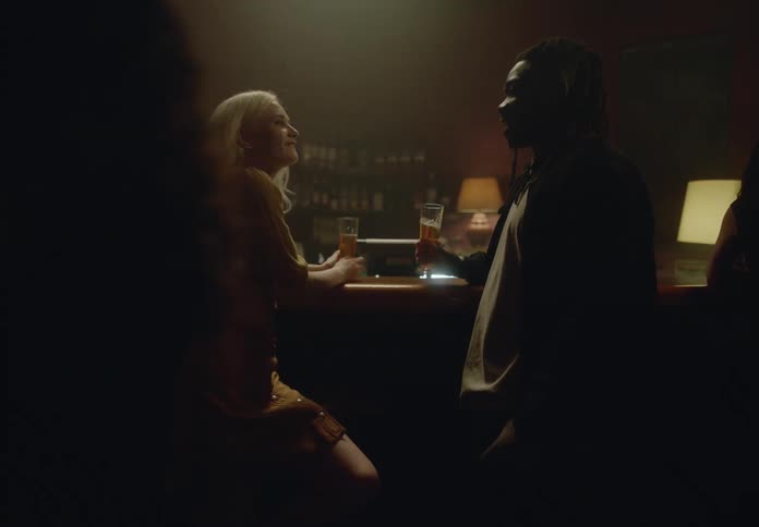 Couple toasting laughing and talking while drinking beer at a bar
