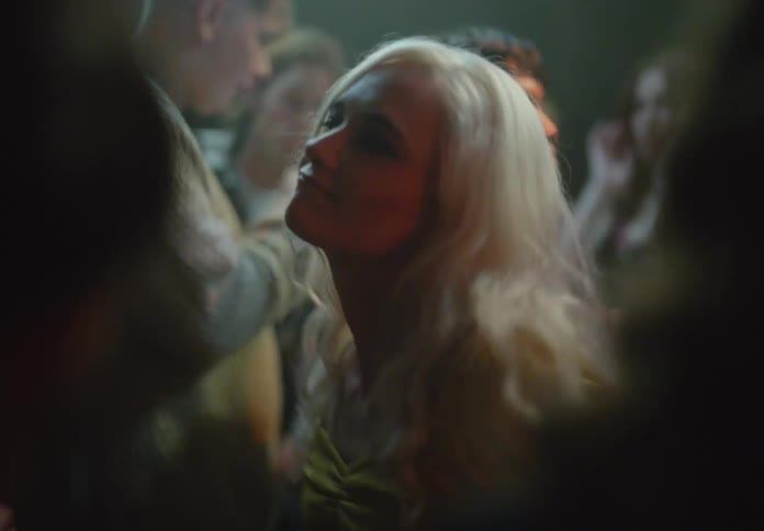 Blonde woman dancing in a club with other people