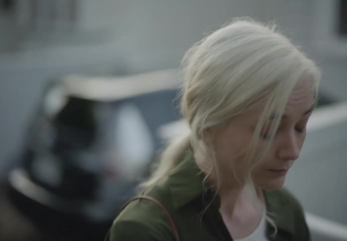 A woman appears to be talking to someone off camera while walking through the suburbs