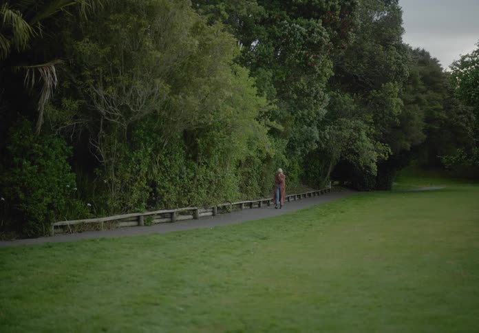 Woman walking outdoors next to dense trees