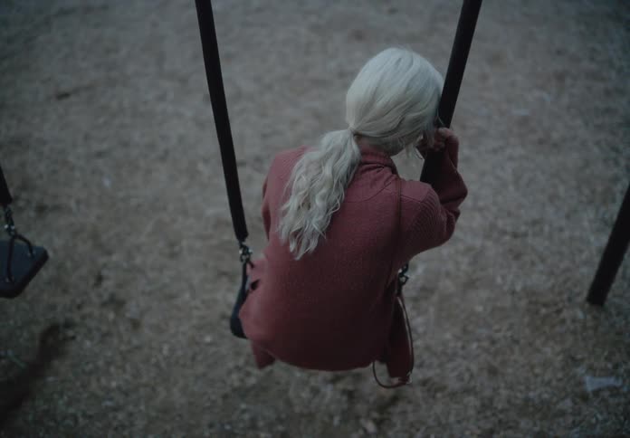 Blonde woman crying feeling sad sitting on a swing