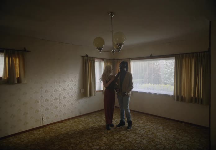 Man and woman holding hands entering an empty room in a house
