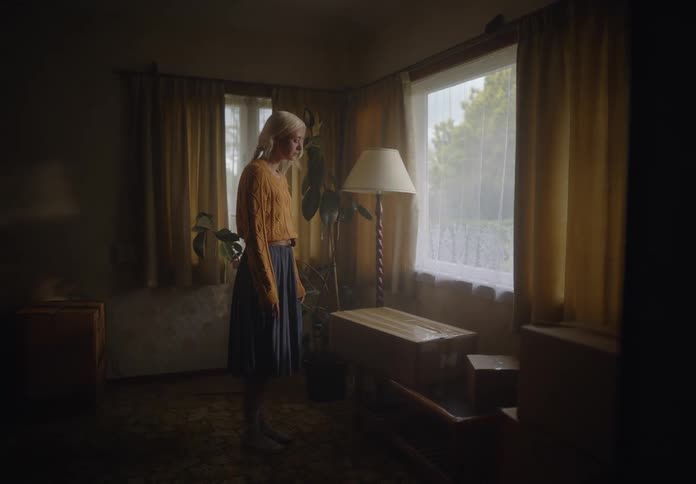 Blonde woman looking out the window while standing in a room of the house