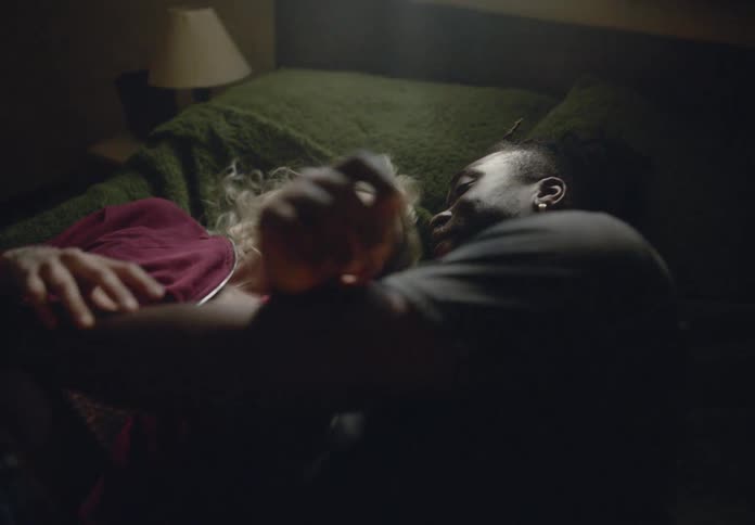 Biracial couple running into bedroom falling on bed to cuddle