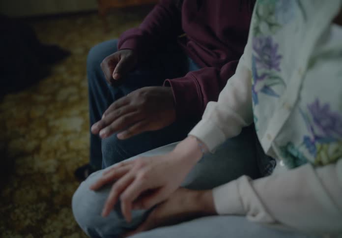 Woman handing a heart necklace to a man sitting next to her who gets up and walks away