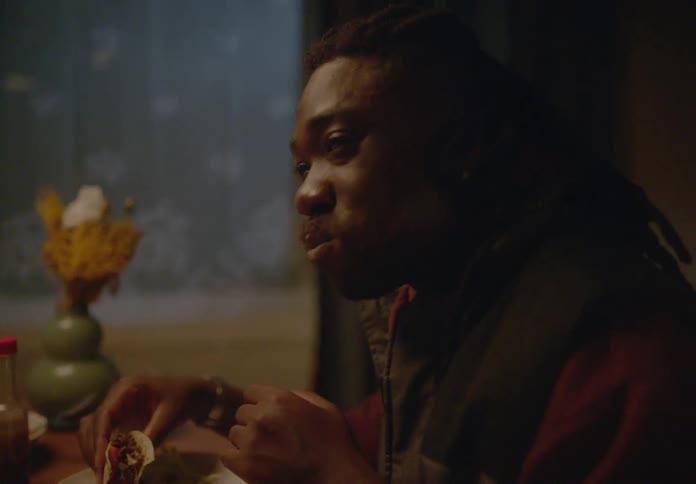 Portrait of a happy man sitting and talking while eating a taco