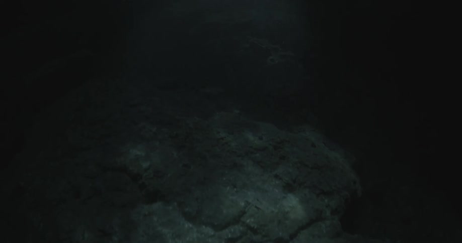 Sunlight is casting shadows on a rock formation in the ocean