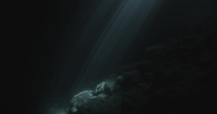 Light shines underwater on the rocks