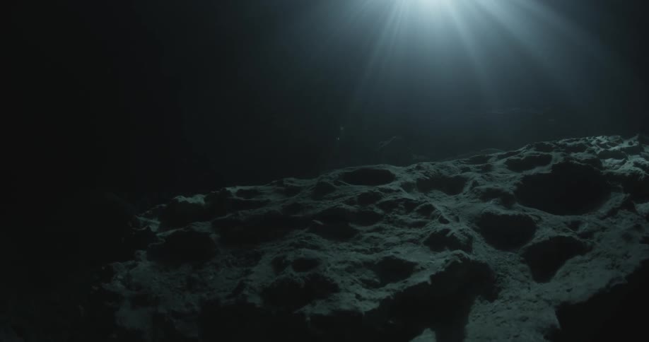 An underwater scene that is dark and the rocks are barely visible