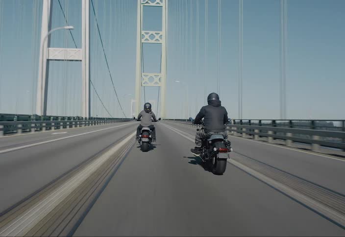 Two motorcycles crossing a suspension bridge