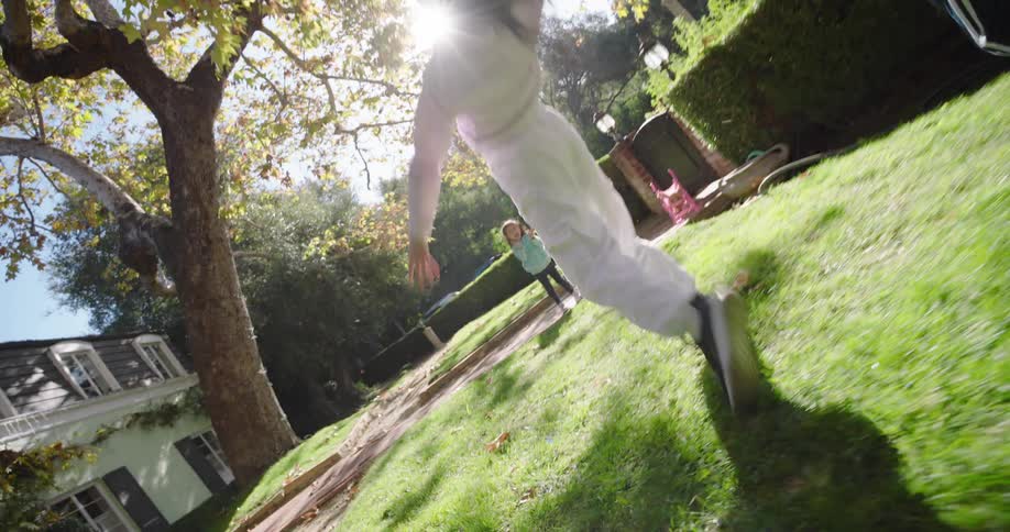 Children are playing on a grassy lawn performing cartwheels on a sunny day