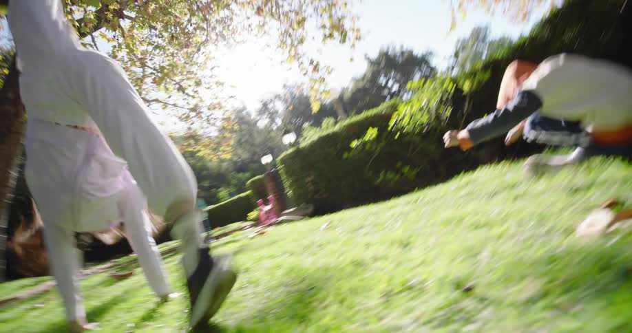 A teenage girl performs cartwheels while playing with her brother and little sister in their front yard
