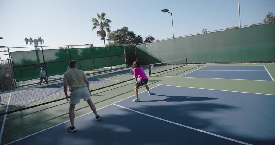 Some people playing tennis on a court with different colors painted on the floor