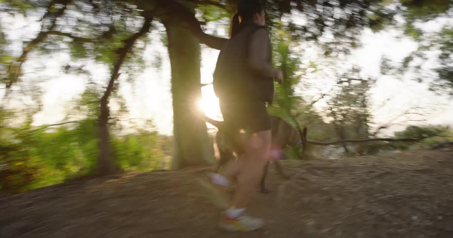 Woman and her dog running up a hiking trail in the woods