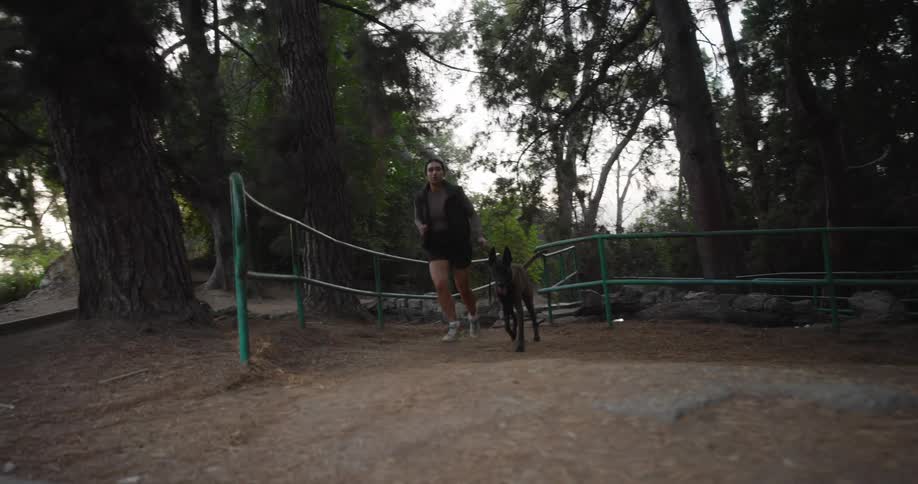 Woman running down a trail with a dog