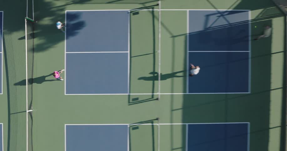A woman hits a tennis ball with a racket while playing in teams of two on the court
