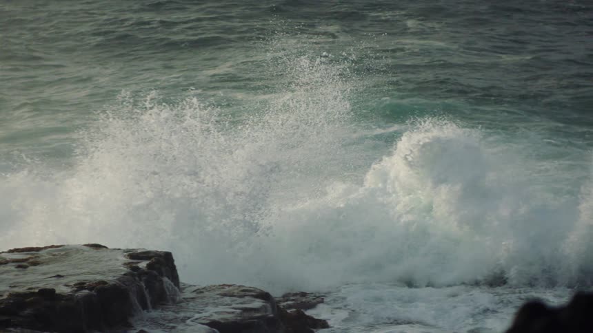 Ocean waters impact heavily on rocks in the foreground