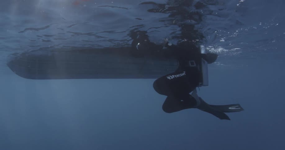 A diver swims alongside a boat