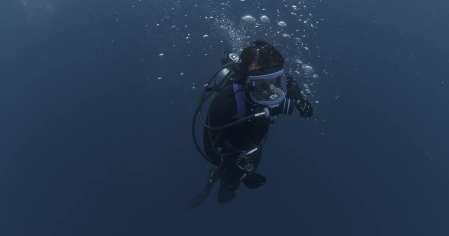 A diver swims in the ocean while bubbles float around him