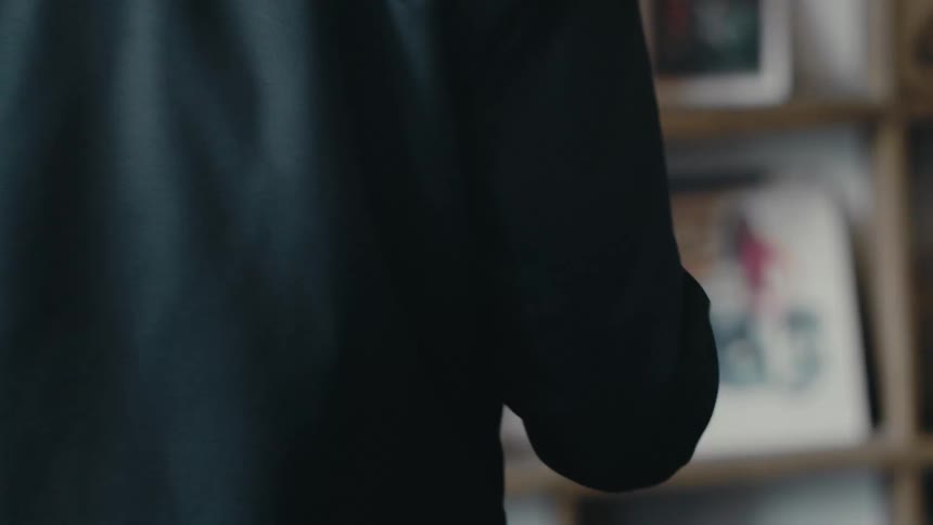 A man with chapped hands picks up a paper cup of coffee from a coffee shop counter