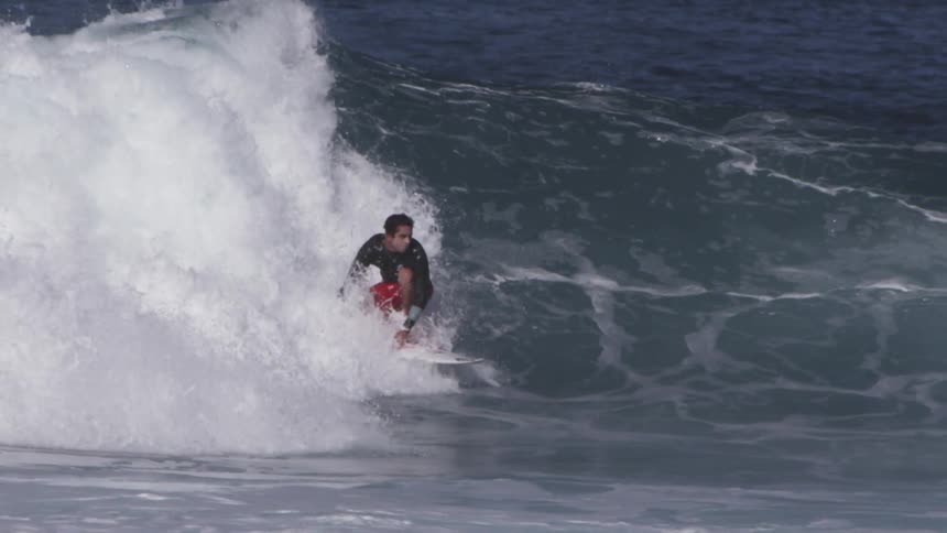 A man surfs on an ocean wave