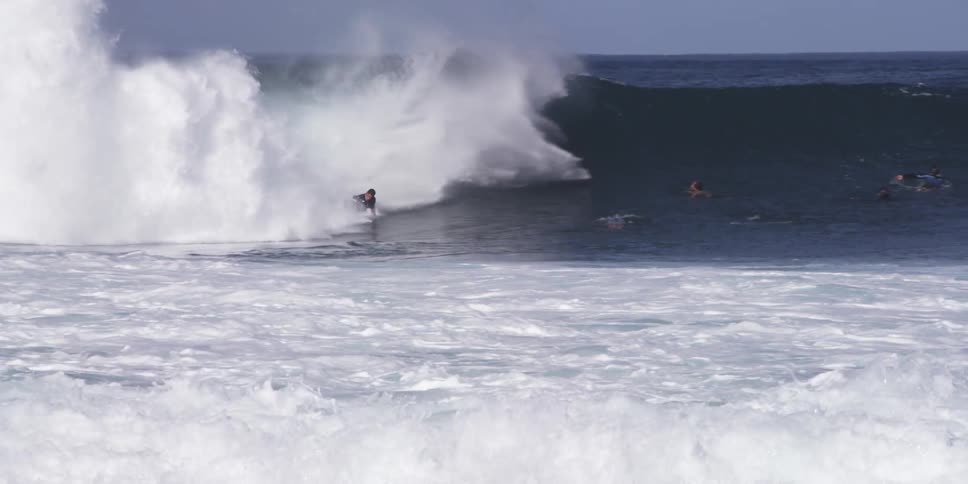 A large wave carries some surfers