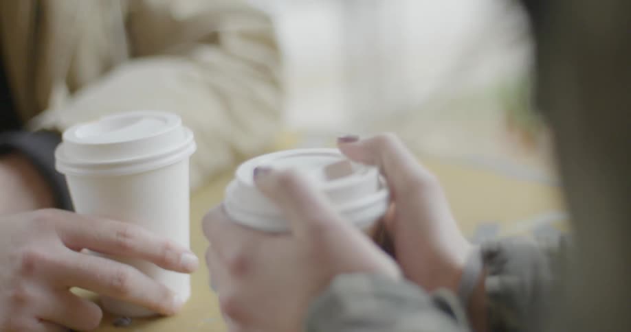 Two people sit down with coffee cups