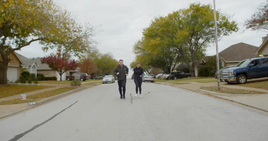 A couple jog down a residential road