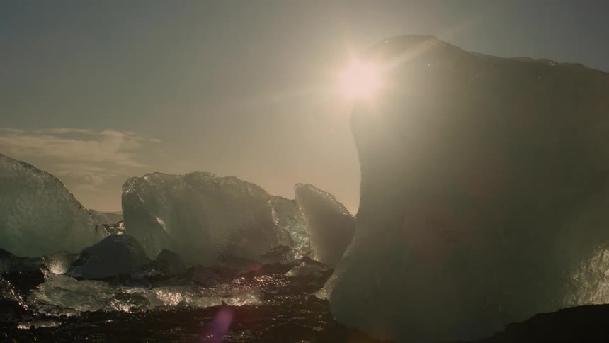 Blocks of ice carved by wind and water glisten in the sunlight in an arctic landscape
