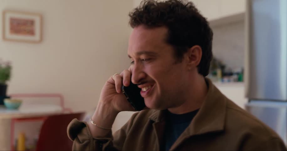 A man is talking on his cell phone while using his laptop