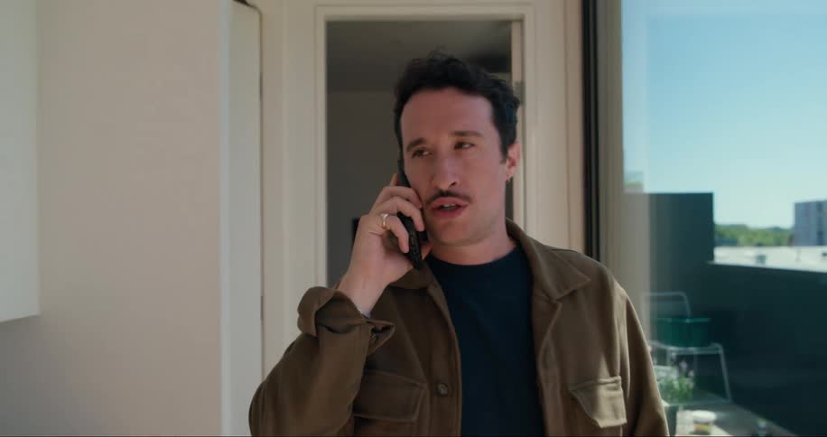 Man talking on cell phone while walking down hallway of house