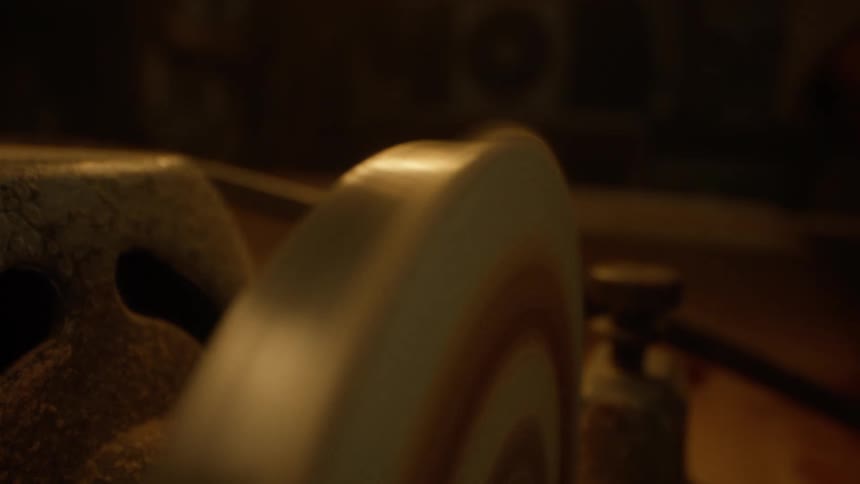 A polishing wheel spins in a dimly lit workshop