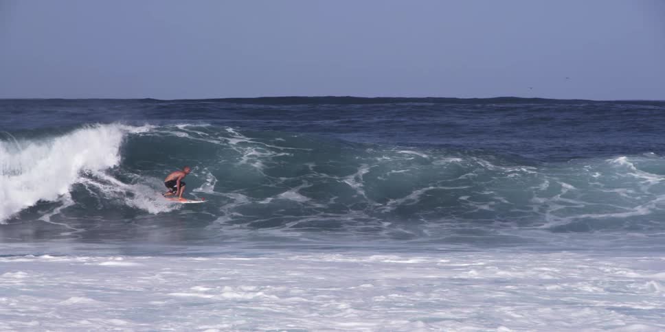 Person surfs large ocean waves