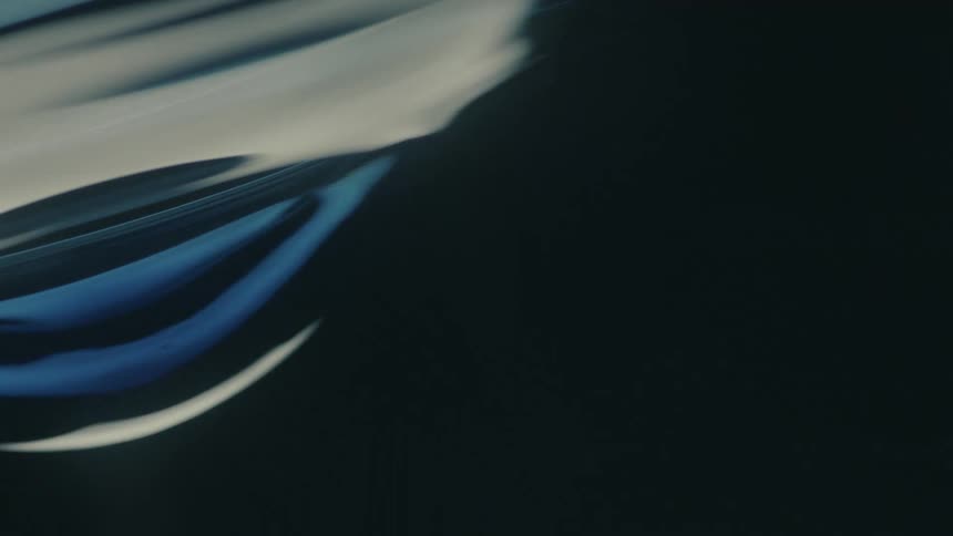 Electric light flows across the dark exterior of a vehicle