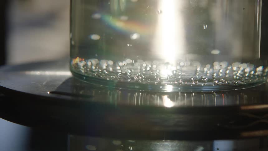 Bubbles rising from bottom of a clear jar fill with liquid