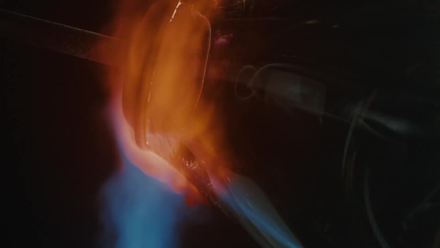 A glass vase is being heated by an open red flame capturing the glassblowing process