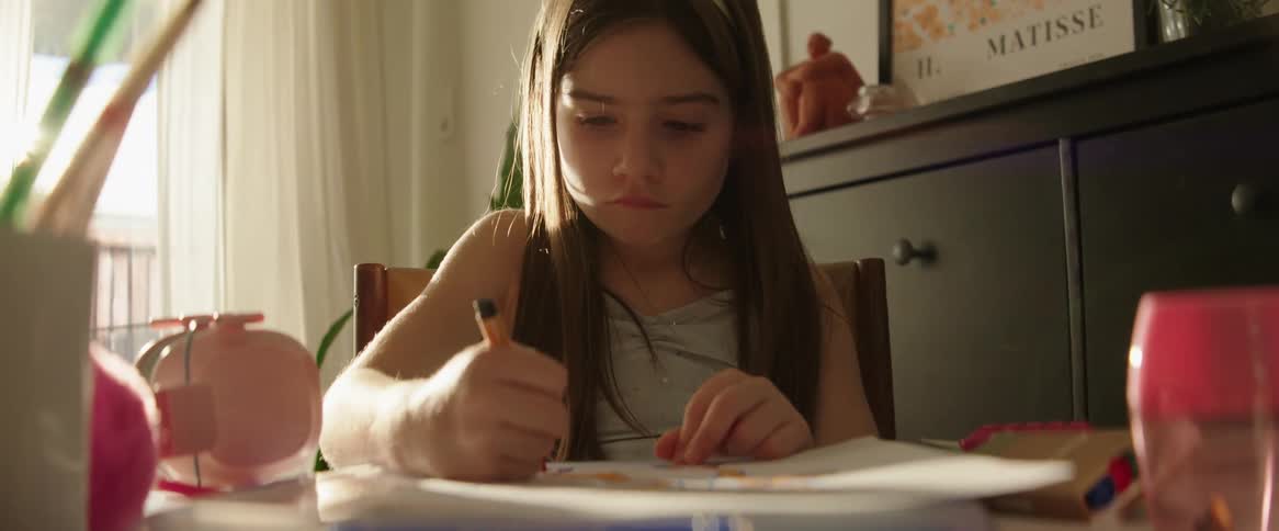 A girl sits a home drawing