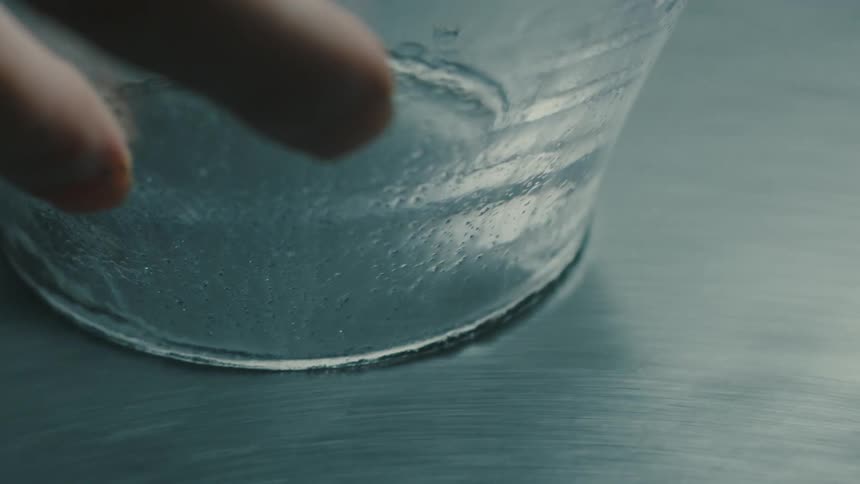Closeup of a hand sanding the edge of a glass vase on a rotating table