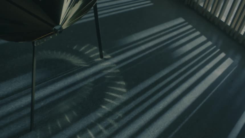 A chairs shadow stretches across a floor in a pattern of light and dark lines
