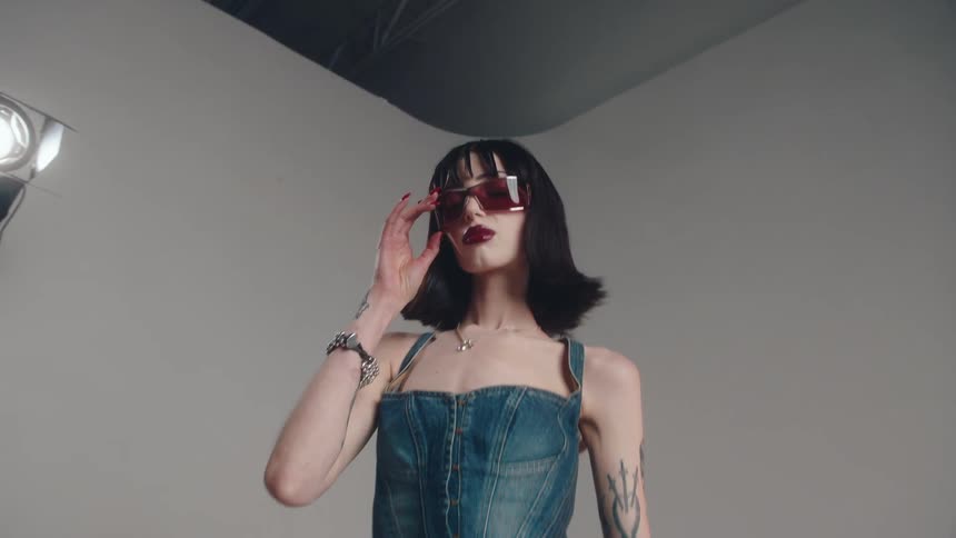 Woman models sunglasses and a denim outfit during a photo shoot