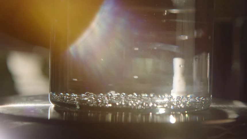 A clear glass jar holds a collection of small silver bubbles with a few floating up