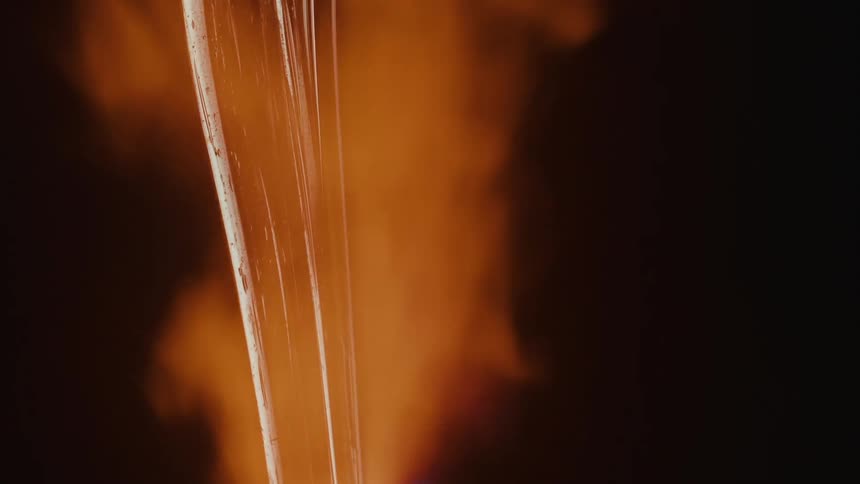 Flame flowing across a piece of molten glass changes color from orange to blue