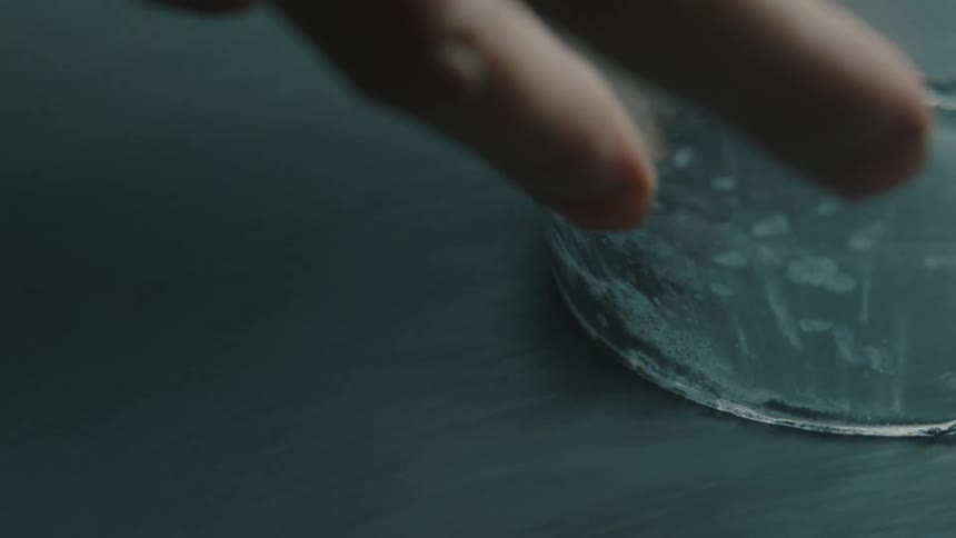 Hand holding a glass cup and molding it on a surface