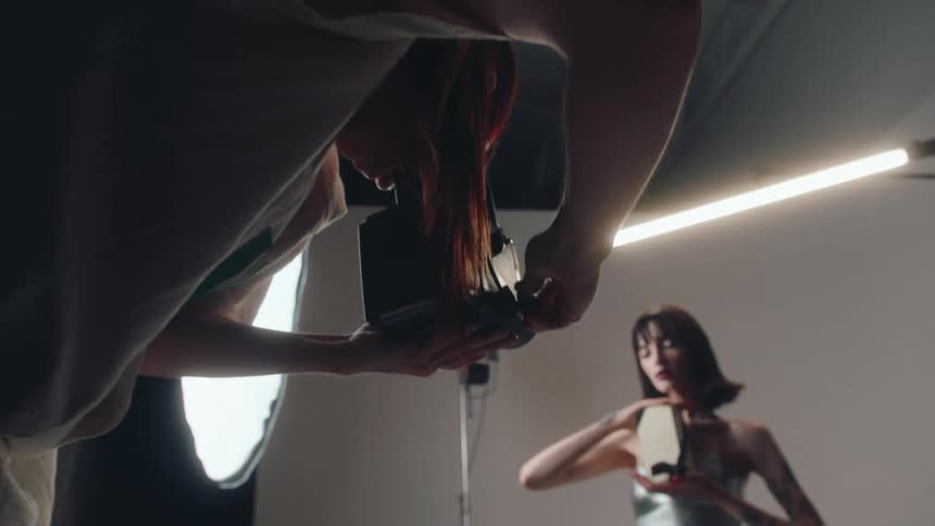 Professional photographer photographing a woman in a studio who holds an object with her hands